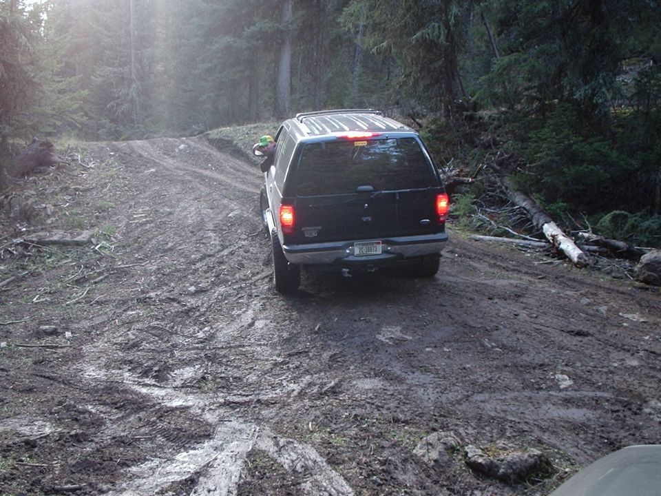 Black Ford Explorer driving on a muddy forest road
