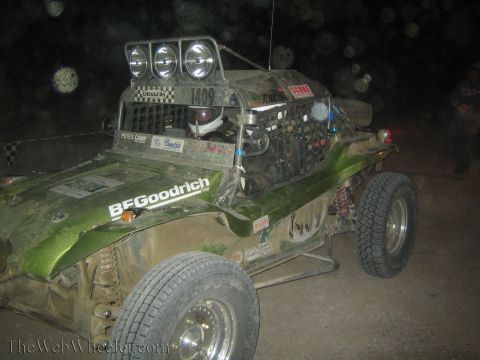 1990 Ford Bronco - green tube-frame off-road dune buggy numbered 1409 with three roof lights and BFGoodrich decals sits on a dark course at night.