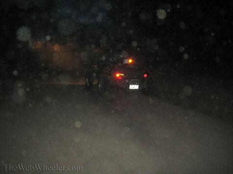 1990 Ford Bronco - off-road buggy drives away into darkness, its red tail lights glowing and a license plate visible at the rear.