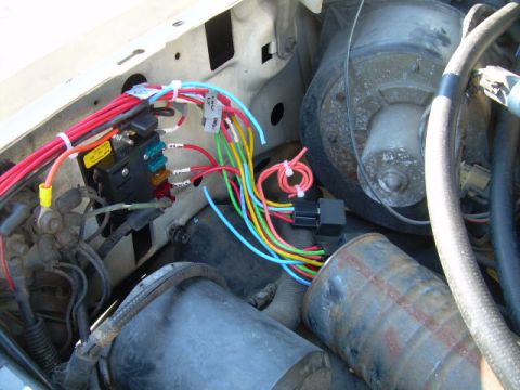 1988 Ford Bronco - Close-up of an engine bay showing a fuse box and a complex wiring harness with many colorful wires.