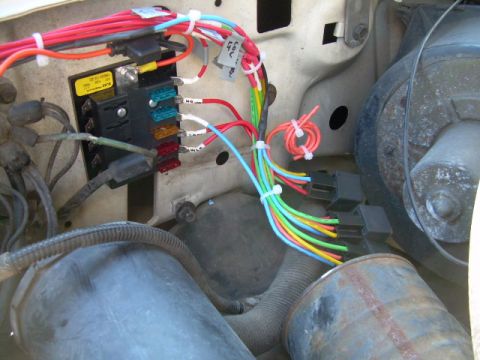 1988 Ford Bronco - A complex wiring harness and fuse box are visible in the engine compartment of a vehicle.
