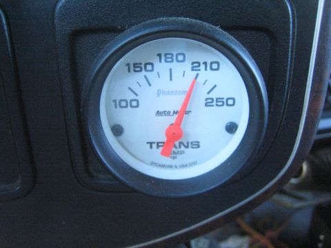 1990 Ford Bronco - white-faced Auto Meter Phantom transmission temperature gauge mounted in a dash pod reads about 210 degrees F.