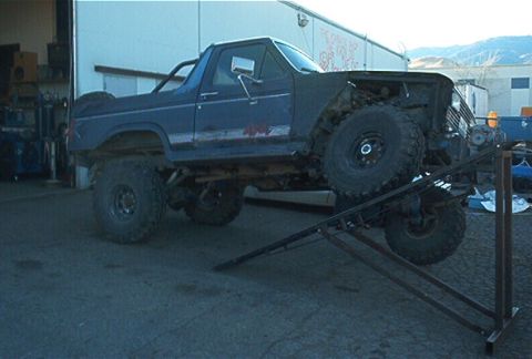 1986 Ford Bronco - This heavily modified Ford Bronco is positioned on a ramp, with its hood off.