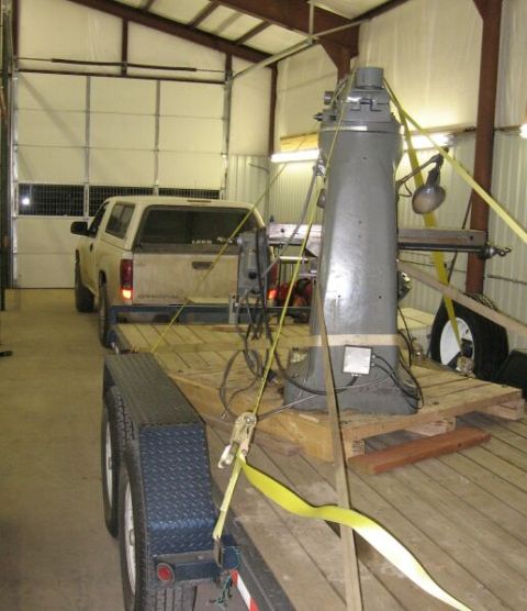 1986 Ford Ranger - A pickup truck is parked inside a garage, towing a trailer loaded with a large industrial machine.