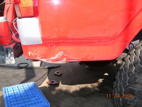 1985 Ford Bronco - Damage and repair work on the rear quarter panel of a vehicle, with a large tire in view.