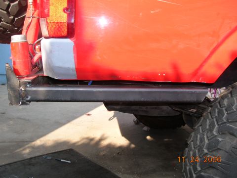 1985 Ford Bronco - Custom rock sliders installed on the side of a red SUV, with a large tire in view.