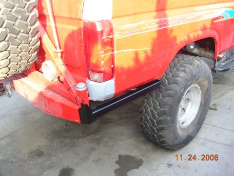1985 Ford Bronco - The rear section of a red SUV is shown, a spare tire and off-road tires.