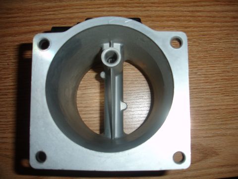 1993 Ford Taurus - A throttle body part is shown against a wooden background.