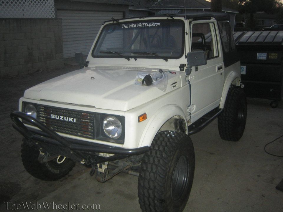 White 1987 Suzuki Samurai with off-road tires and brush guard
