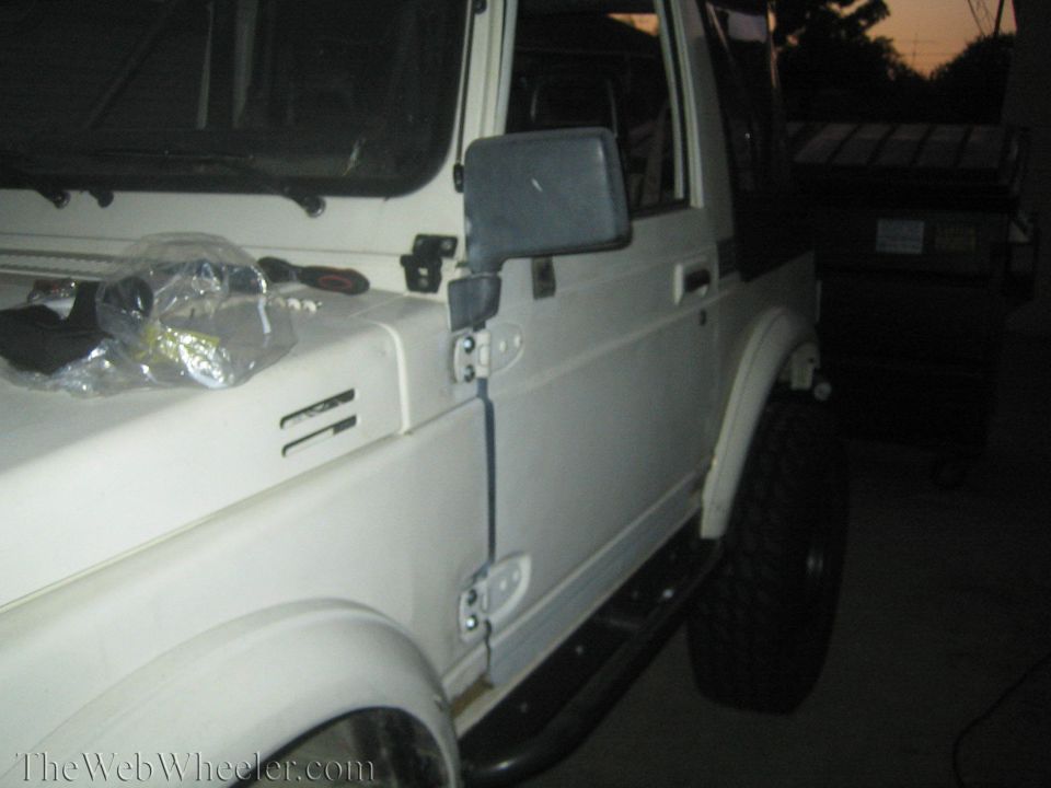 White Suzuki Samurai, front quarter view, showing side door, fender, and hood details