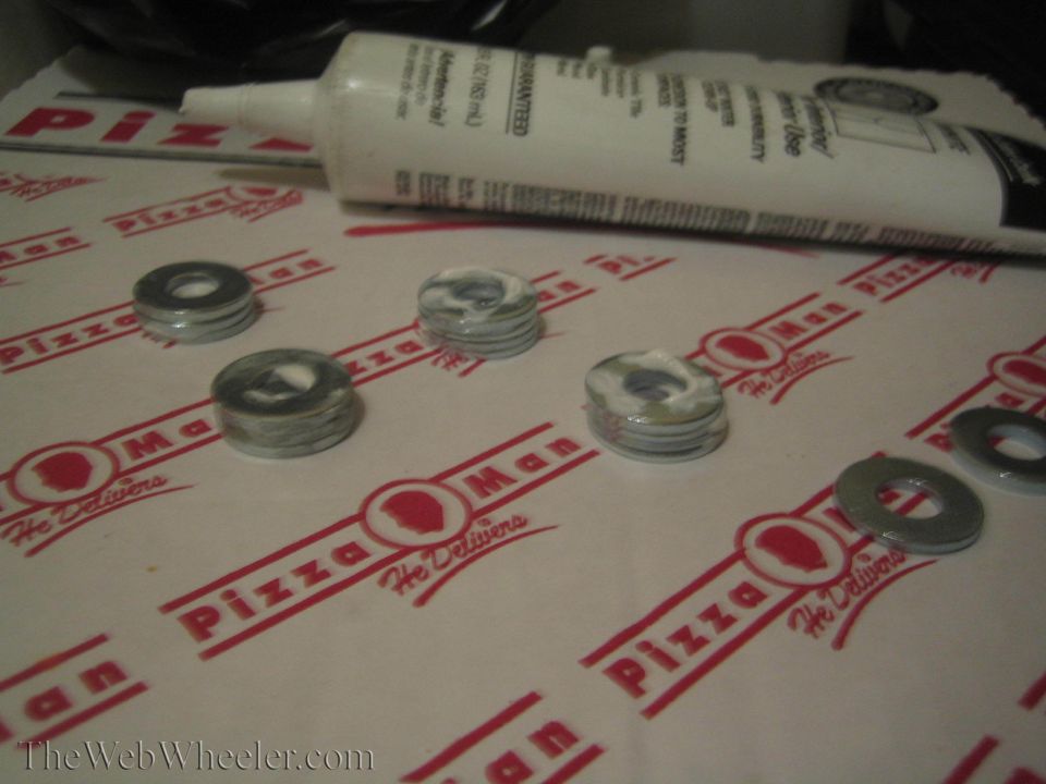 Four stacks of washers and one loose washer on a Pizza Man liner with a tube of sealant