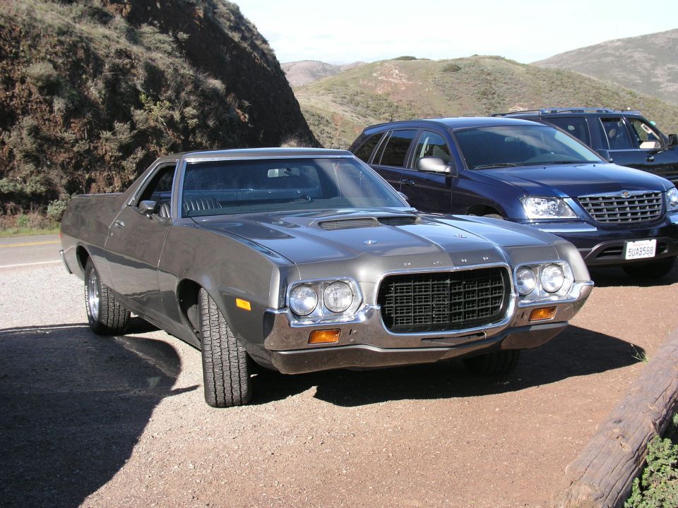 Gray 1972 Ford Ranchero parked on gravel, front 3/4 view. Another SUV is behind it