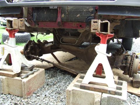 1995 Ford Bronco - Front suspension and frame of a vehicle undergoing maintenance, raised on jack stands.