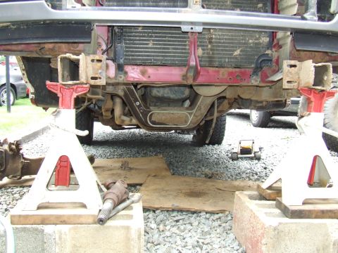 1995 Ford Bronco - The front end of a vehicle is raised on jack stands, revealing the radiator and undercarriage components.