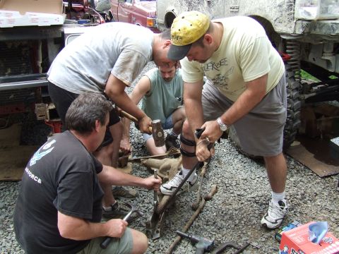 1995 Ford Bronco - Mechanics perform repairs on a vehicle's suspension system outdoors.