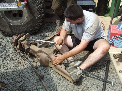 1995 Ford Bronco - A man works on a disassembled front axle assembly, with a large tire visible in the background.