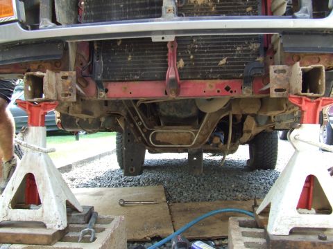 1995 Ford Bronco - The front underside of a lifted truck is supported by jack stands, revealing its suspension components and radiator.