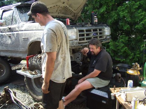 1995 Ford Bronco - Men working on a lifted Ford truck with the hood open.