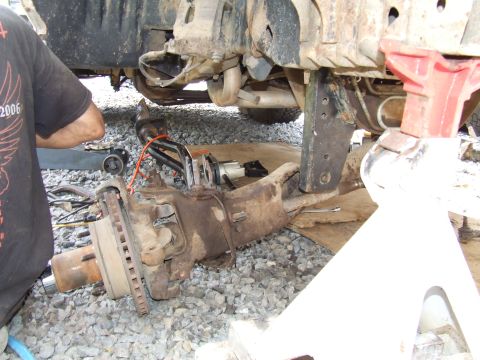 1995 Ford Bronco - Close-up of a vehicle's front axle and suspension system undergoing maintenance.