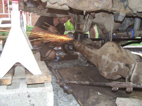 1995 Ford Bronco - Mechanic works on a vehicle's axle, sparks flying from the grinder.
