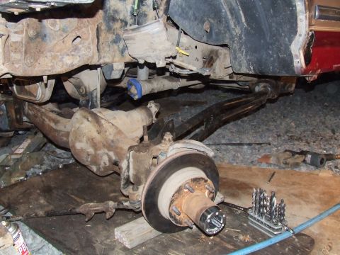 1995 Ford Bronco - The rear axle and suspension of a vehicle are shown, with tools laid out nearby, suggesting ongoing maintenance or repair.