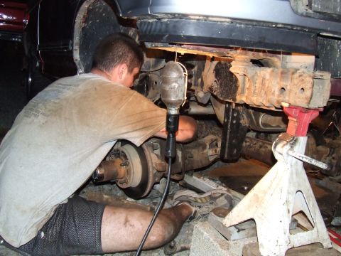 1995 Ford Bronco - Mechanic works on the rear axle and suspension of a 1995 Ford Bronco.
