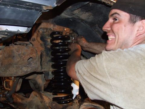 1995 Ford Bronco - Mechanic installs new coil spring on a vehicle's suspension.