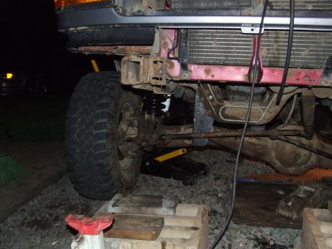 1995 Ford Bronco - Close-up of the front wheel and suspension of a lifted truck, showing modifications and a jack.