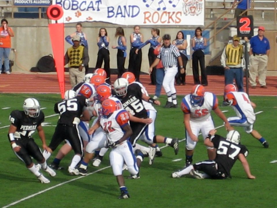 Football players in action on a field, with cheerleaders and a banner in the background