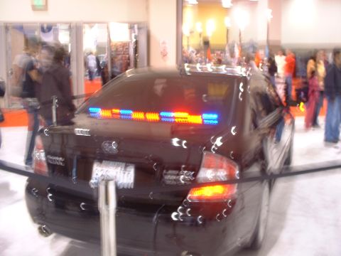 2000 Ford Crown Victoria - A black sedan with a light bar is displayed indoors, possibly at an auto show.