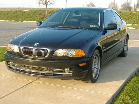 2001 BMW 3 Series - A black BMW 3 Series coupe is parked on a concrete driveway, showing its distinctive grille and headlights.