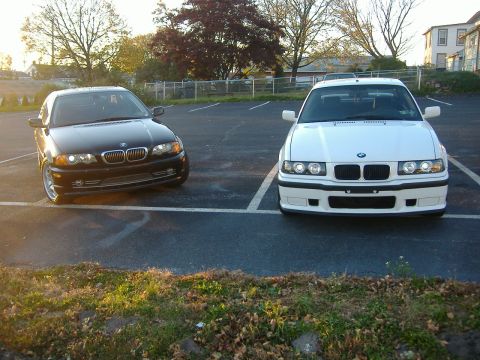 2001 BMW 3 Series - Two BMW 3 Series sedans, one black and one white, are parked in an outdoor lot.
