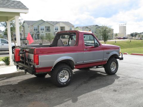 1995 Ford Bronco - This two-tone Ford Bronco is parked in a lot with apartment buildings in the background.