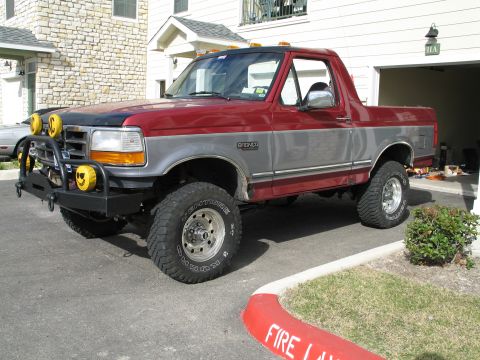 1995 Ford Bronco - This red and gray Ford Bronco features a two-tone paint scheme and off-road modifications.