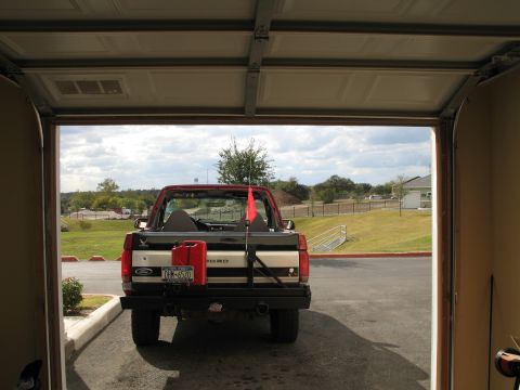 1995 Ford Bronco - A red and black 1995 Ford Bronco is parked outside a garage, ready for an adventure with a jerry can and flag.