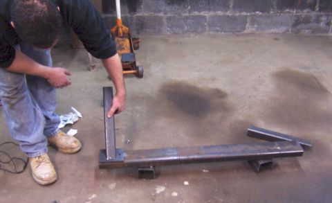 1978 Ford Bronco - A person is working on a metal frame assembly in a garage setting.