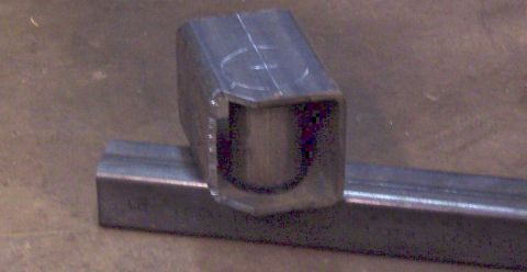 1978 Ford Bronco - Close-up of a metal bracket with a U-shaped opening, placed on a metal bar.