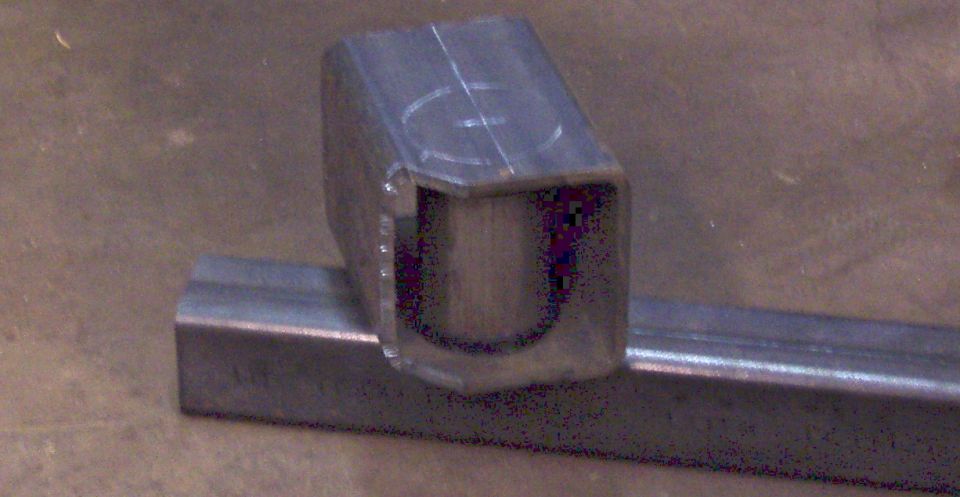 Metal bracket with a U-shaped cutout, resting on a metal bar