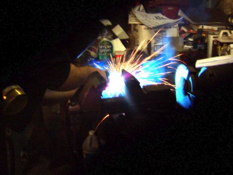 1978 Ford Bronco - A close-up view of welding sparks illuminating a dark workshop environment.