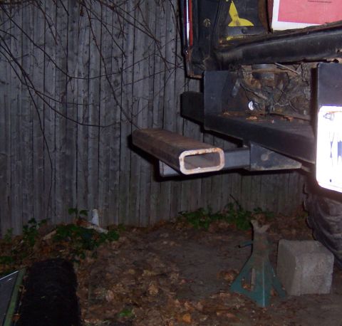 1978 Ford Bronco - The rear of a vehicle is shown with a tow hitch extension attached to the bumper.
