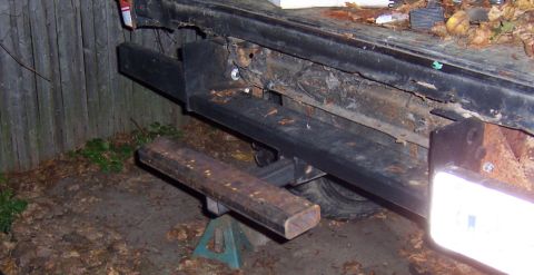 1978 Ford Bronco - The rear of a vehicle shows a custom bumper modification with a step, resting on jack stands.