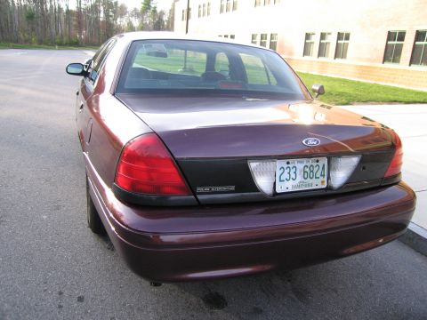 1991 Ford LTD Crown Victoria - Rear view of a dark purple sedan, possibly a Ford Crown Victoria, with a "Police Interceptor" badge visible.