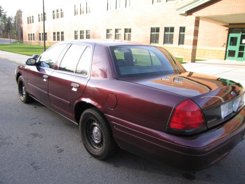 1991 Ford LTD Crown Victoria - This maroon sedan is parked on a street in front of a brick building with green doors.