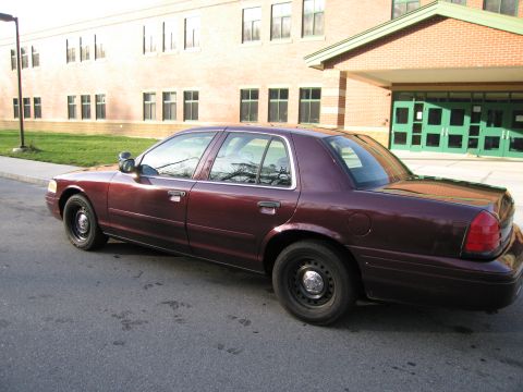 1991 Ford LTD Crown Victoria - This maroon sedan, likely a 1992 Ford Crown Victoria, is parked in front of a brick building.