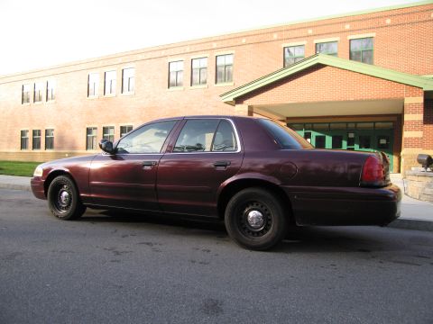 1991 Ford LTD Crown Victoria - This maroon sedan, likely a later model Ford Crown Victoria, is seen from the side parked in front of a brick building.