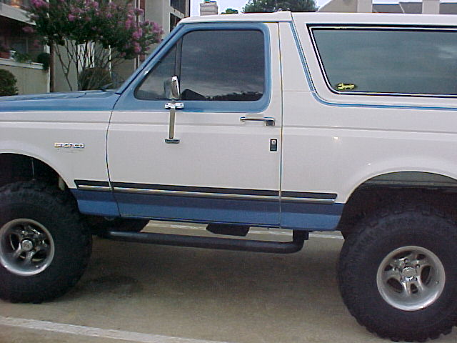 1990 Ford Bronco side profile, white and blue two-tone paint, aftermarket wheels and side steps