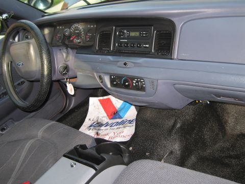 1991 Ford LTD Crown Victoria - The interior of a car shows the dashboard, steering wheel, and center console, with a Valvoline mat on the floor.