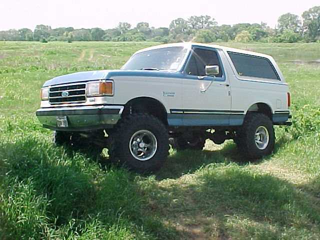 White and blue Ford Bronco parked on a grassy hill