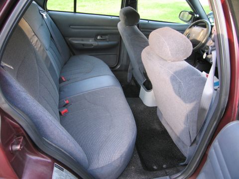 1991 Ford LTD Crown Victoria - The interior of a maroon sedan shows the rear bench seat, front bucket seats, and dashboard area.
