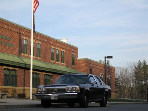 1991 Ford LTD Crown Victoria - Black 1990s Ford Crown Victoria parked in front of a brick building with an American flag.